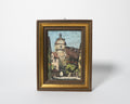 Framed painting of a village scene with a tower on a white background