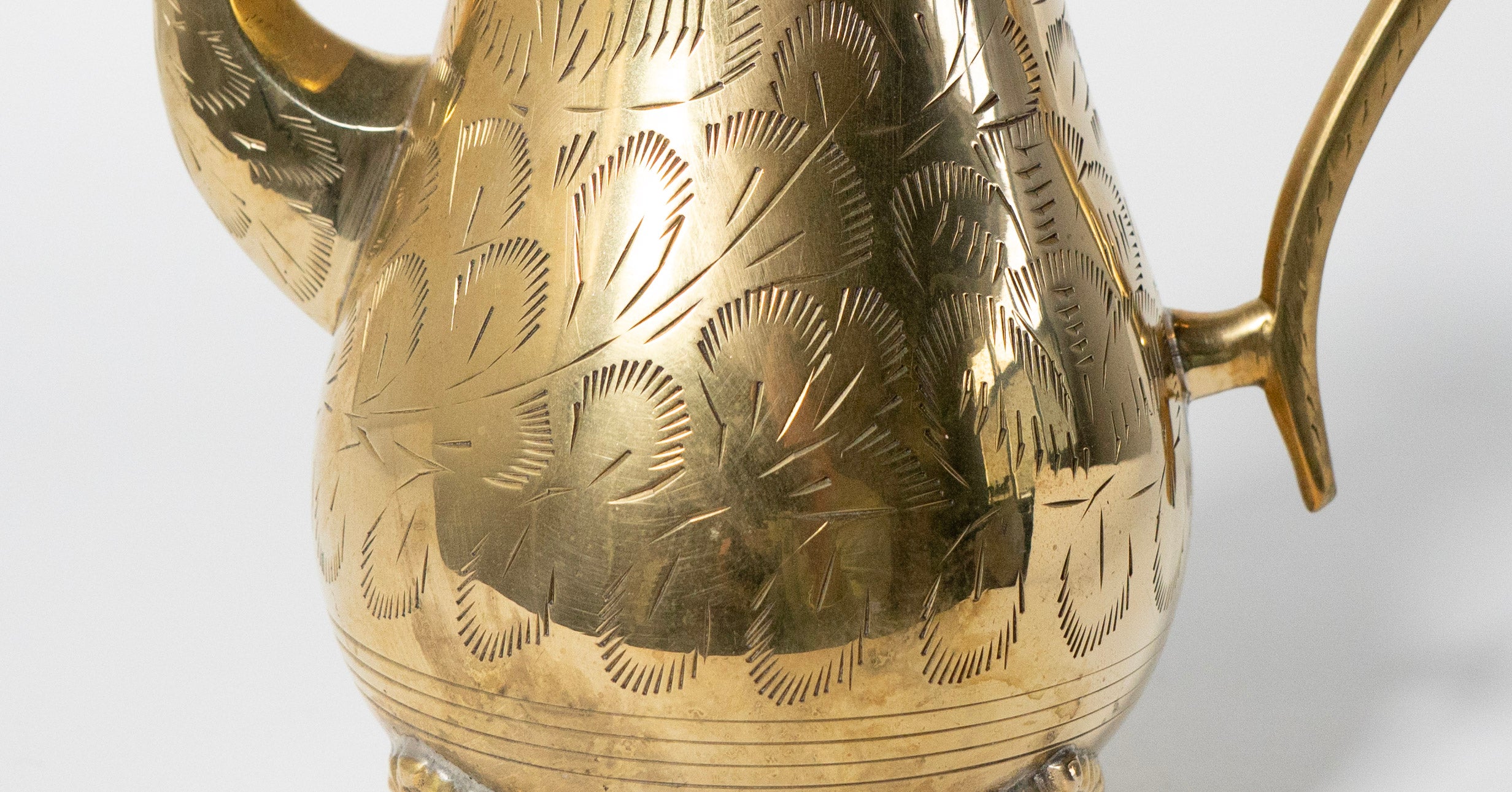 Gold coffee pot with intricate patterns on a white background