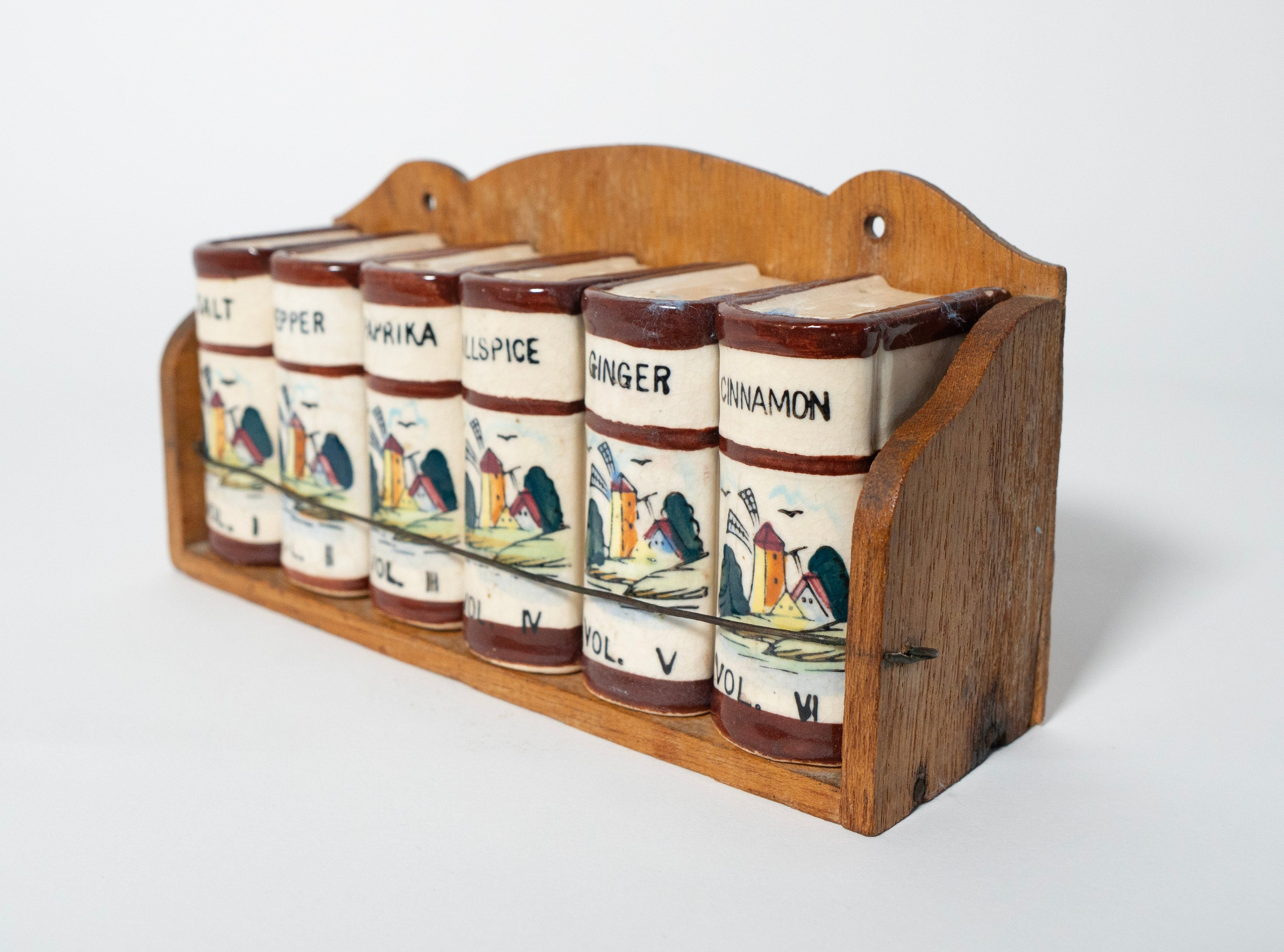 Set of ceramic spice jars with wooden holder on a white background