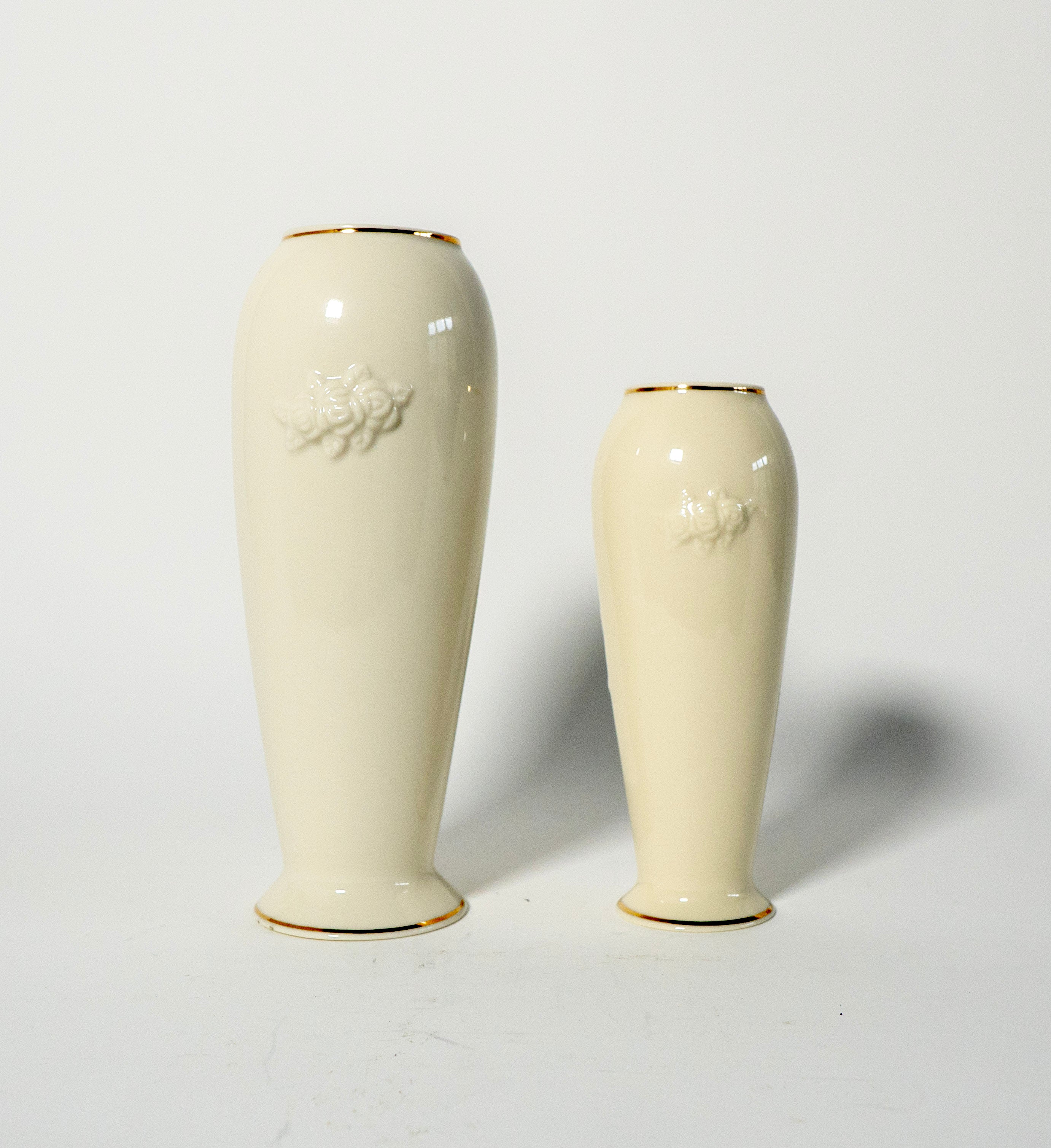 Two cream-colored vases with gold rims on a light gray background