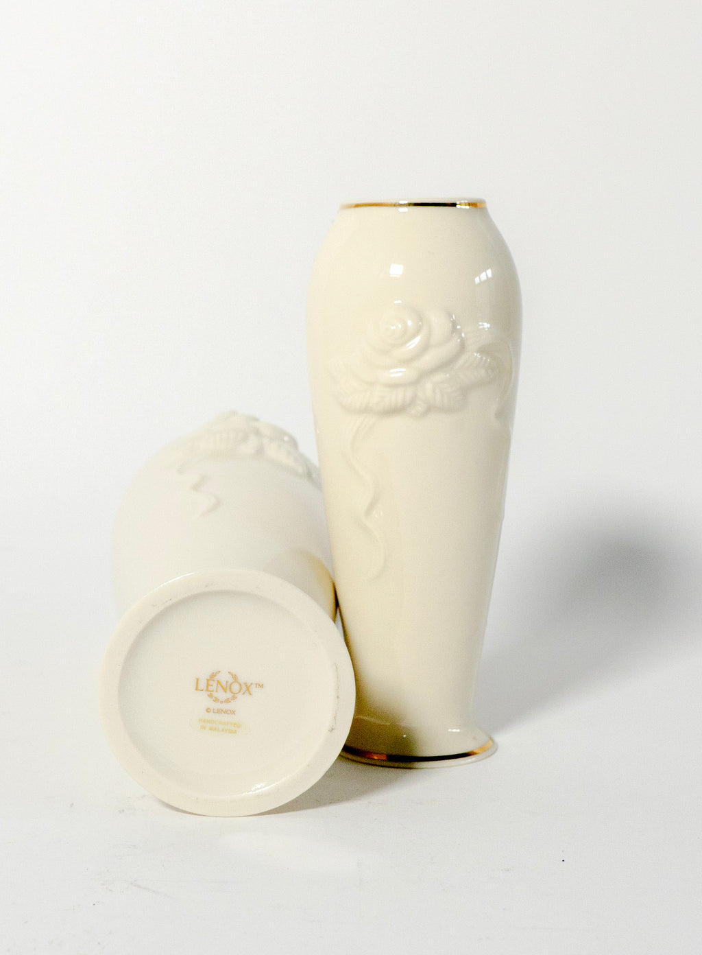 Two white ceramic vases with gold accents on a light gray background