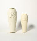 Two white ceramic vases with floral embossing on a light gray background