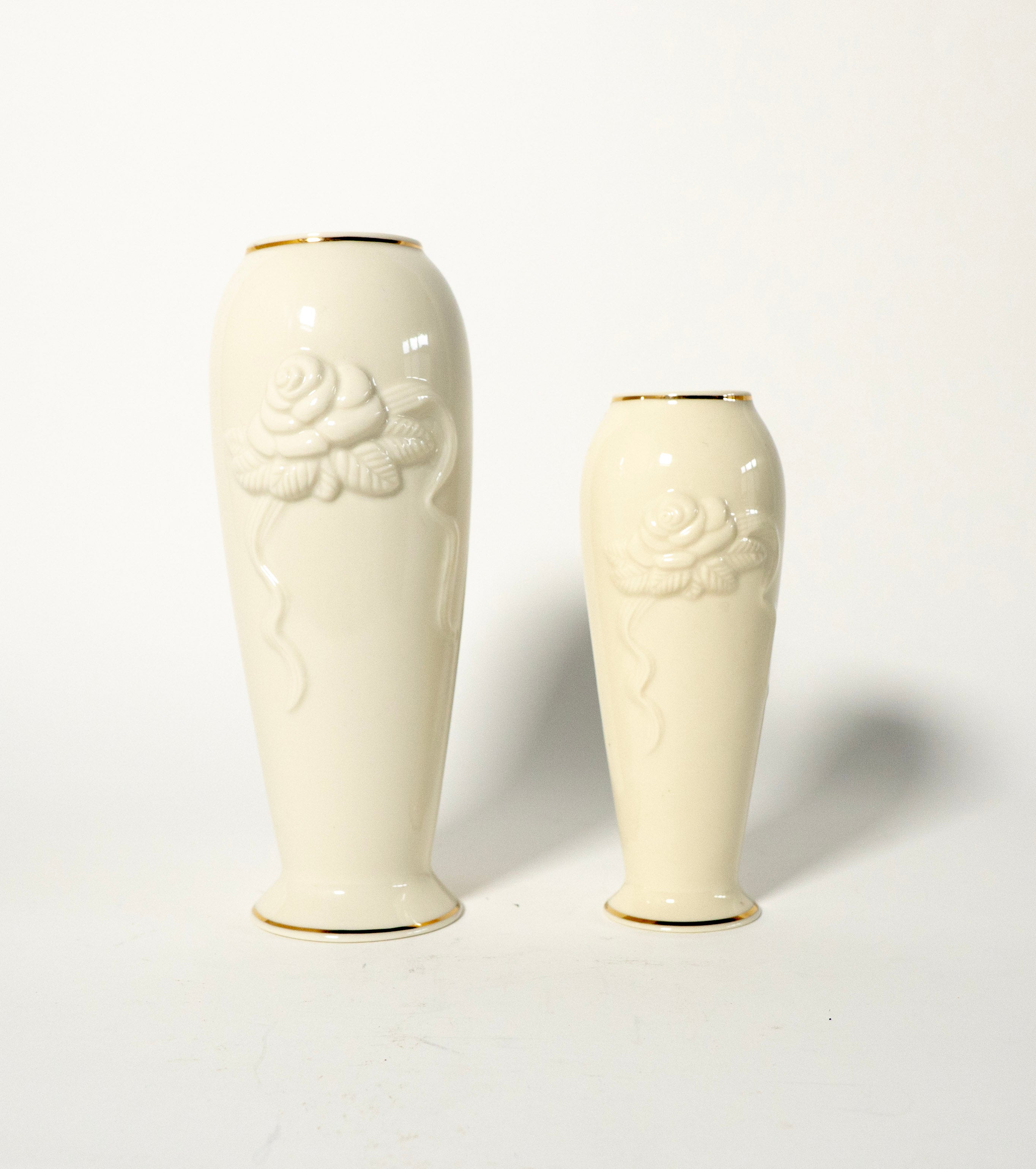 Two white ceramic vases with floral embossing on a light gray background