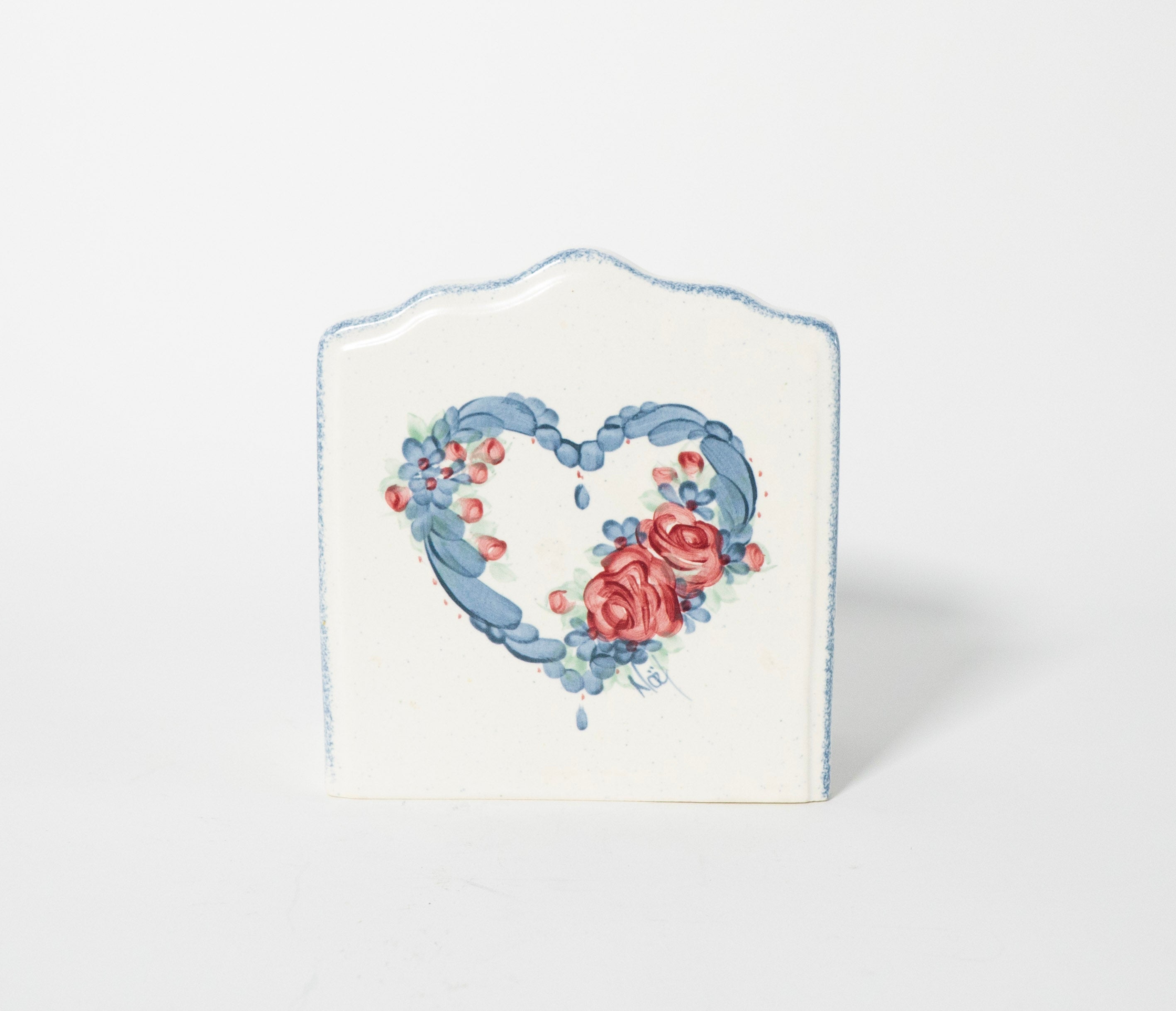 Decorative heart-shaped object with floral design on a white background