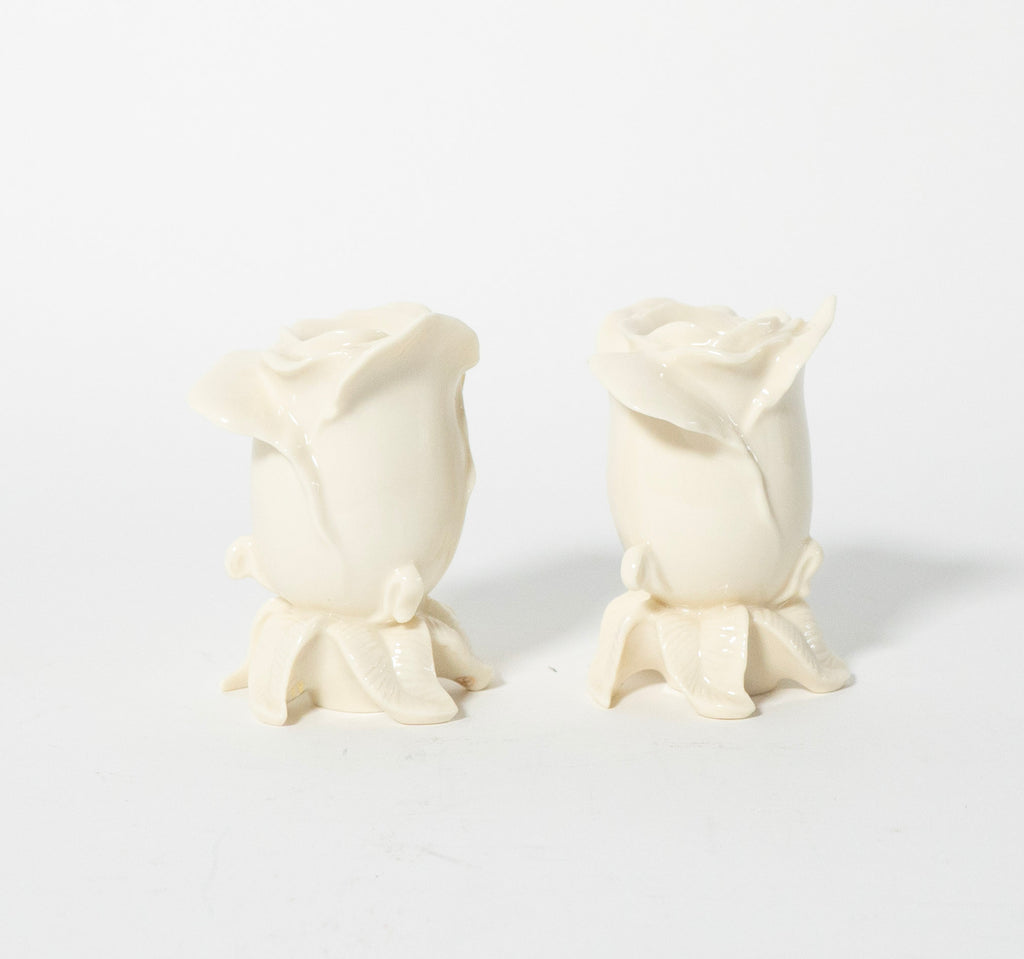 Two white rose-shaped candles on a light gray background