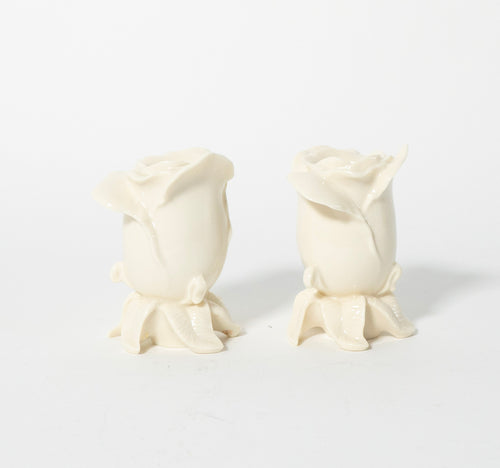 Two white rose-shaped candles on a light gray background