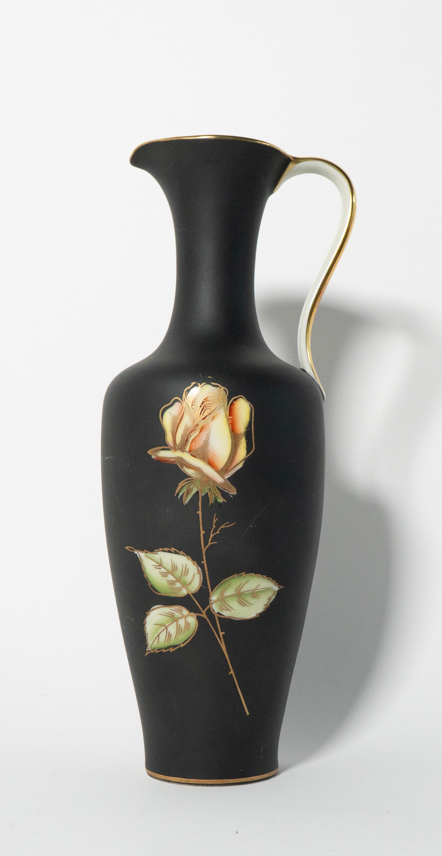 Black vase with a gold rim and a painted rose on a white background