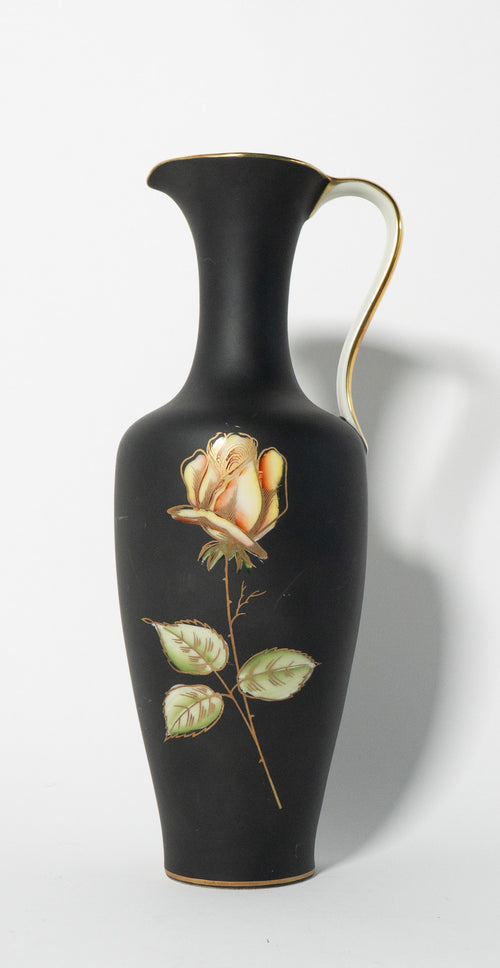 Black vase with a gold rim and a painted rose on a white background