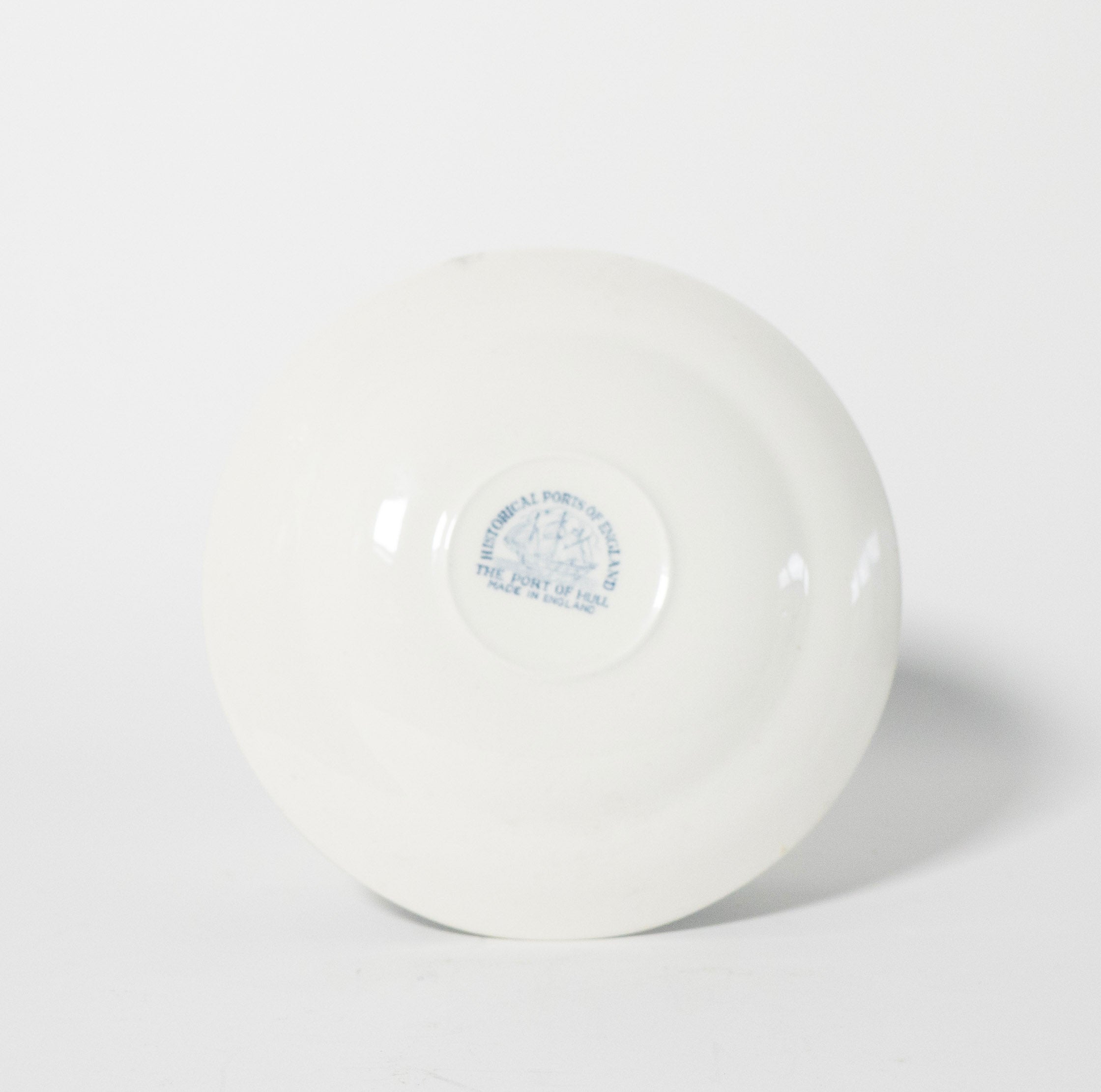 Bottom view of white ceramic plate on a white background