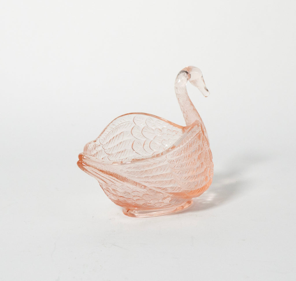 Pink glass swan-shaped bowl on a light gray background