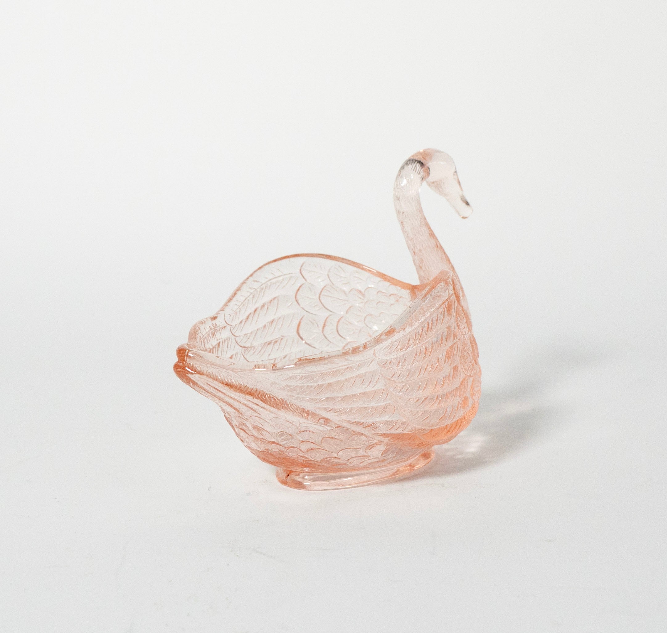 Pink glass swan-shaped bowl on a light gray background