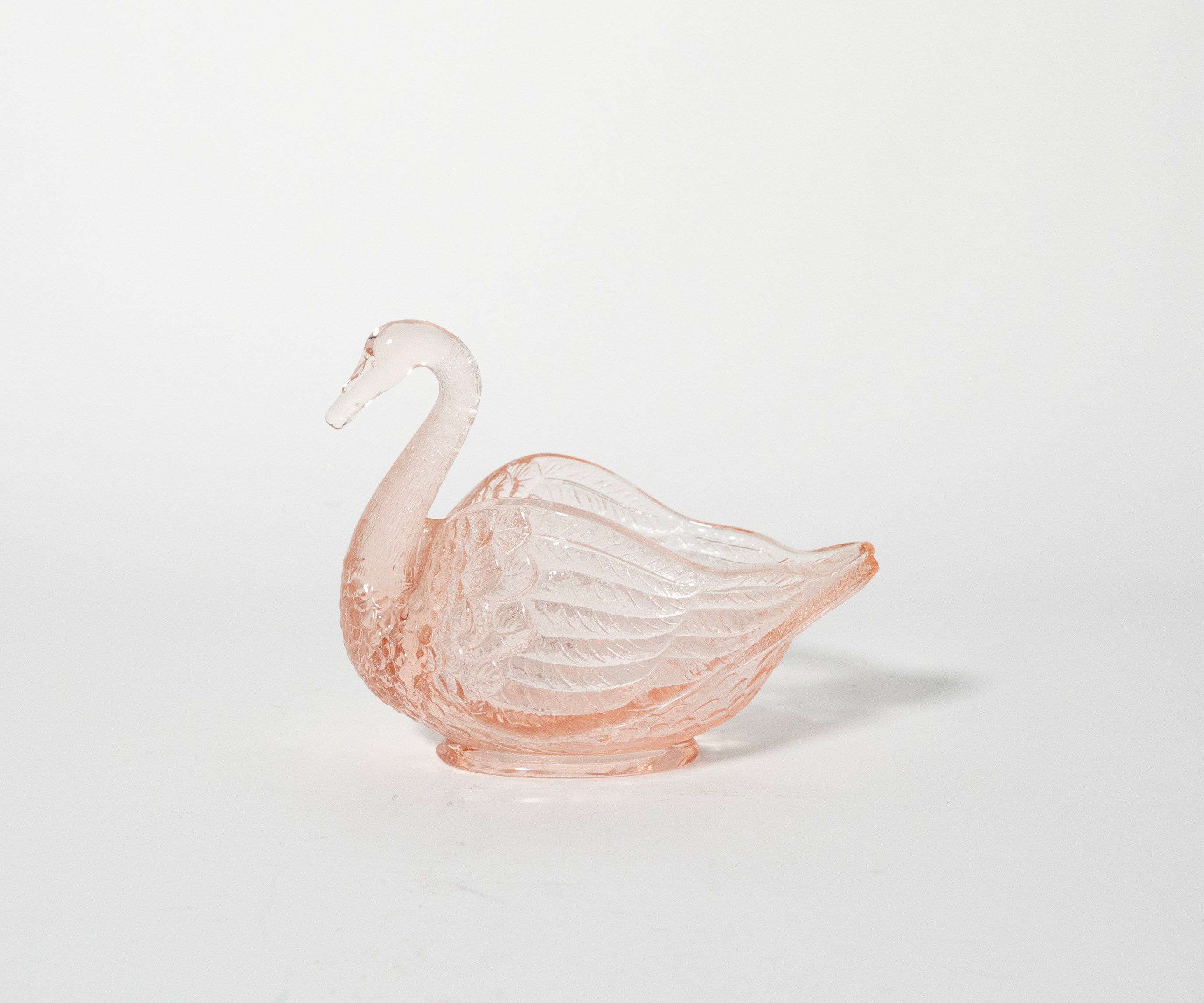 Pink glass swan ornament on a white background
