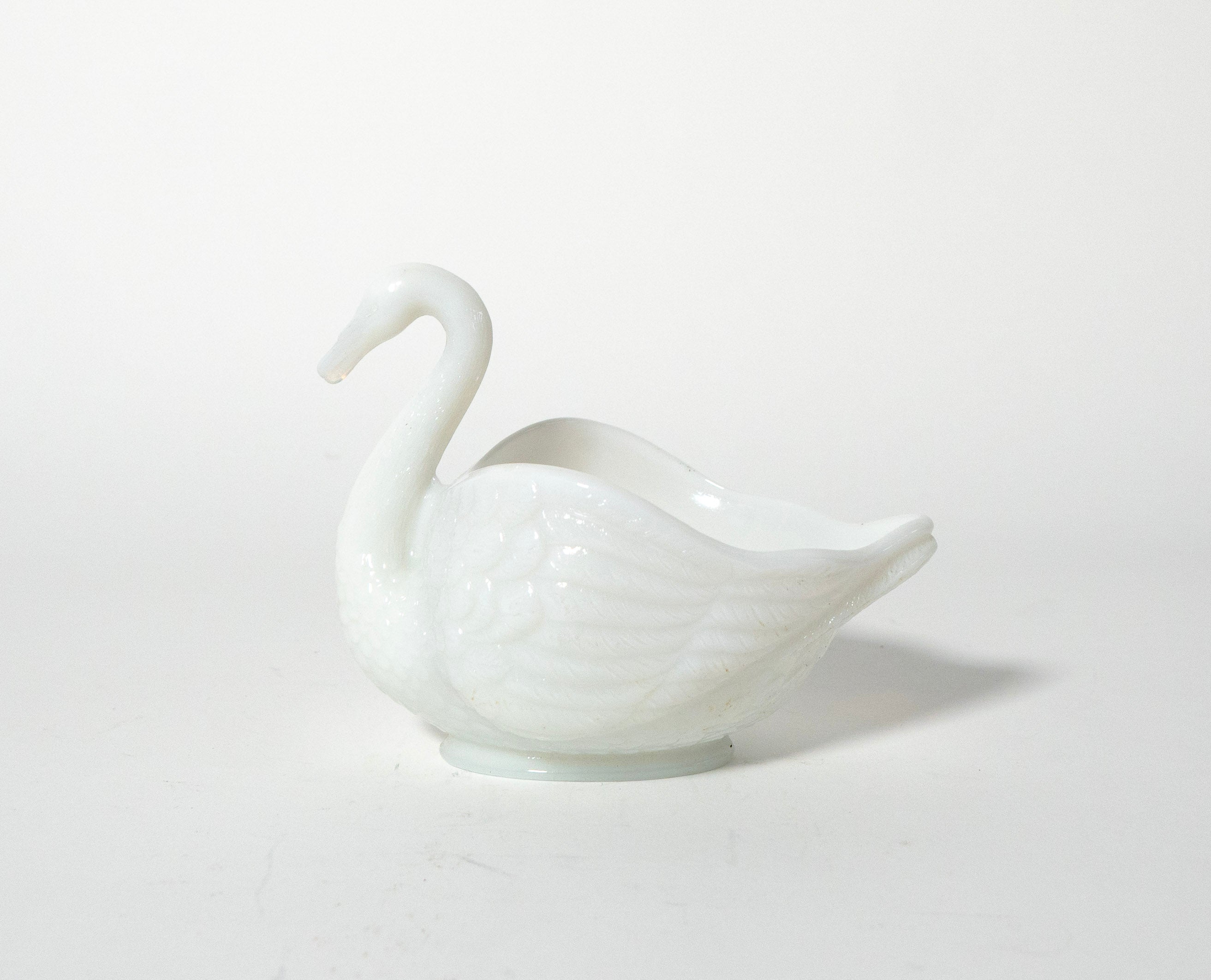 White ceramic swan-shaped object on a light gray background
