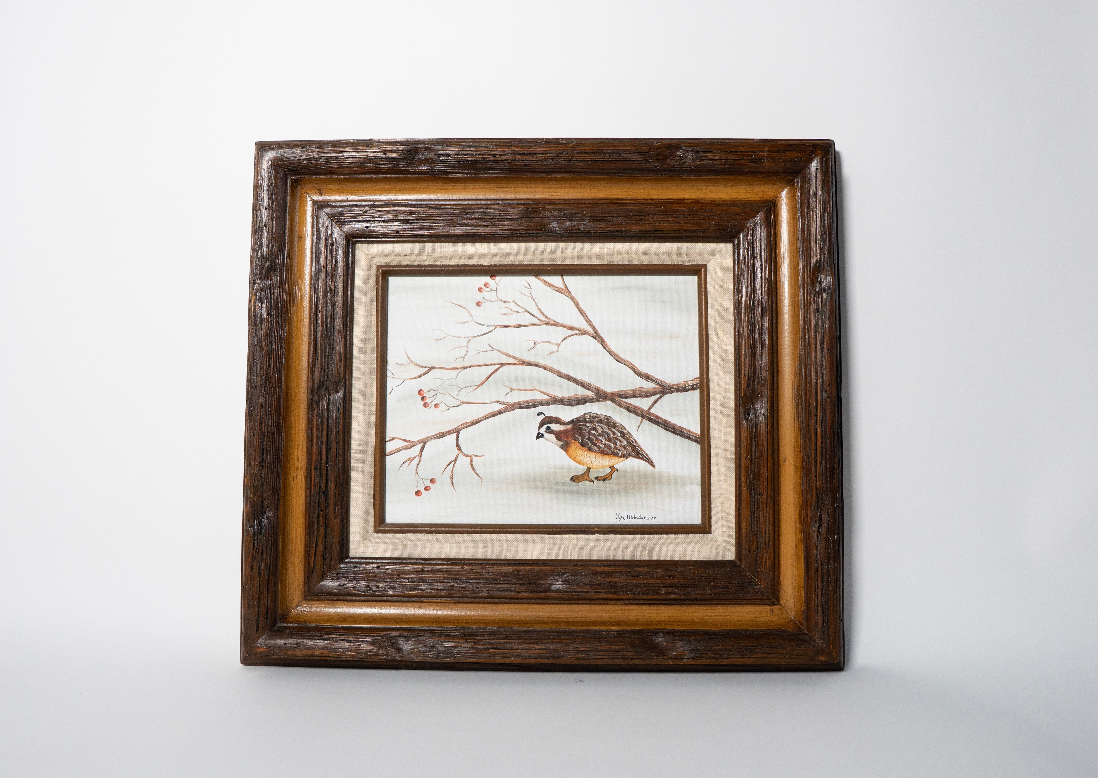 Framed artwork of a bird on a branch with a wooden frame.
