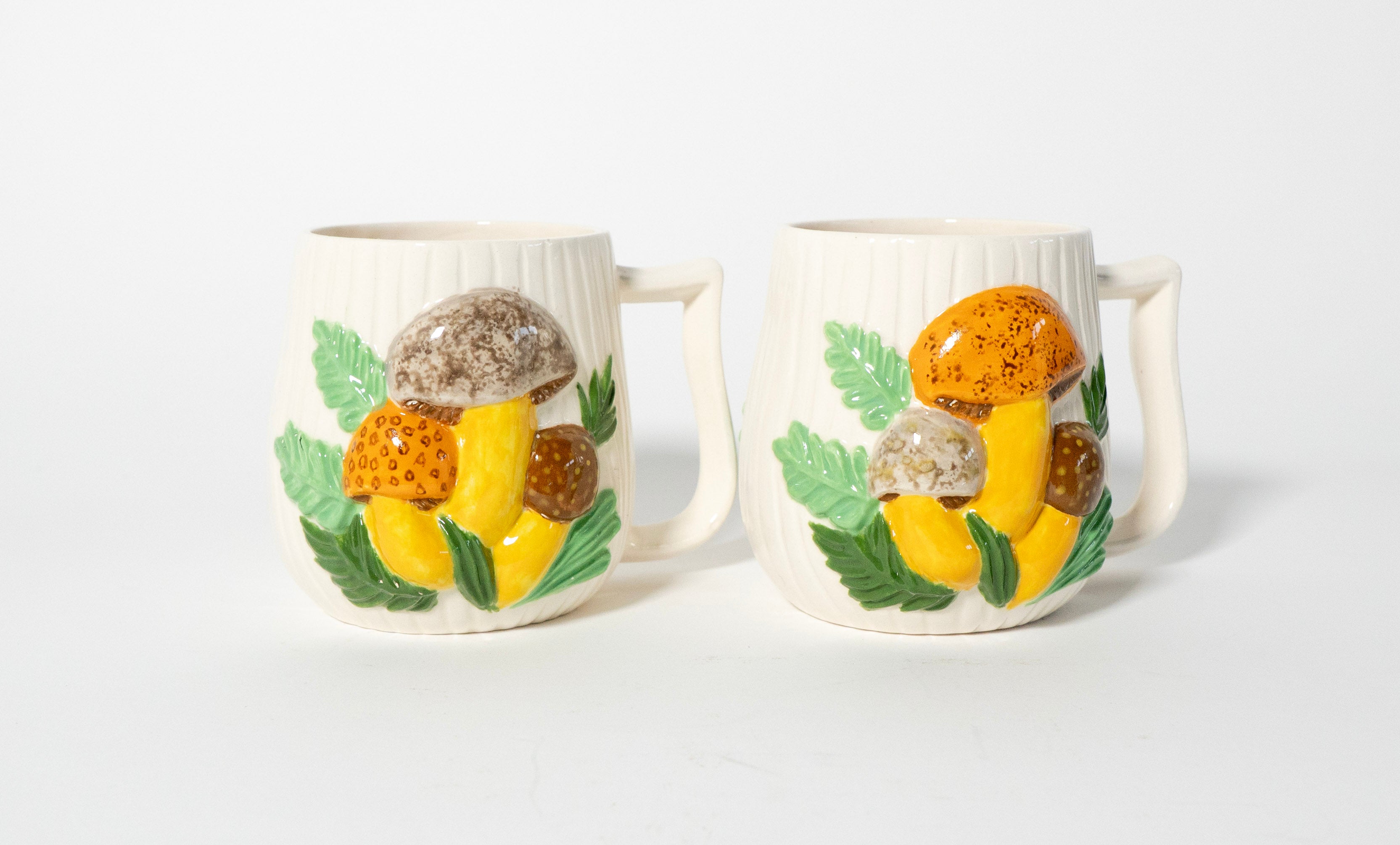 Two ceramic mugs with mushroom designs on a white background