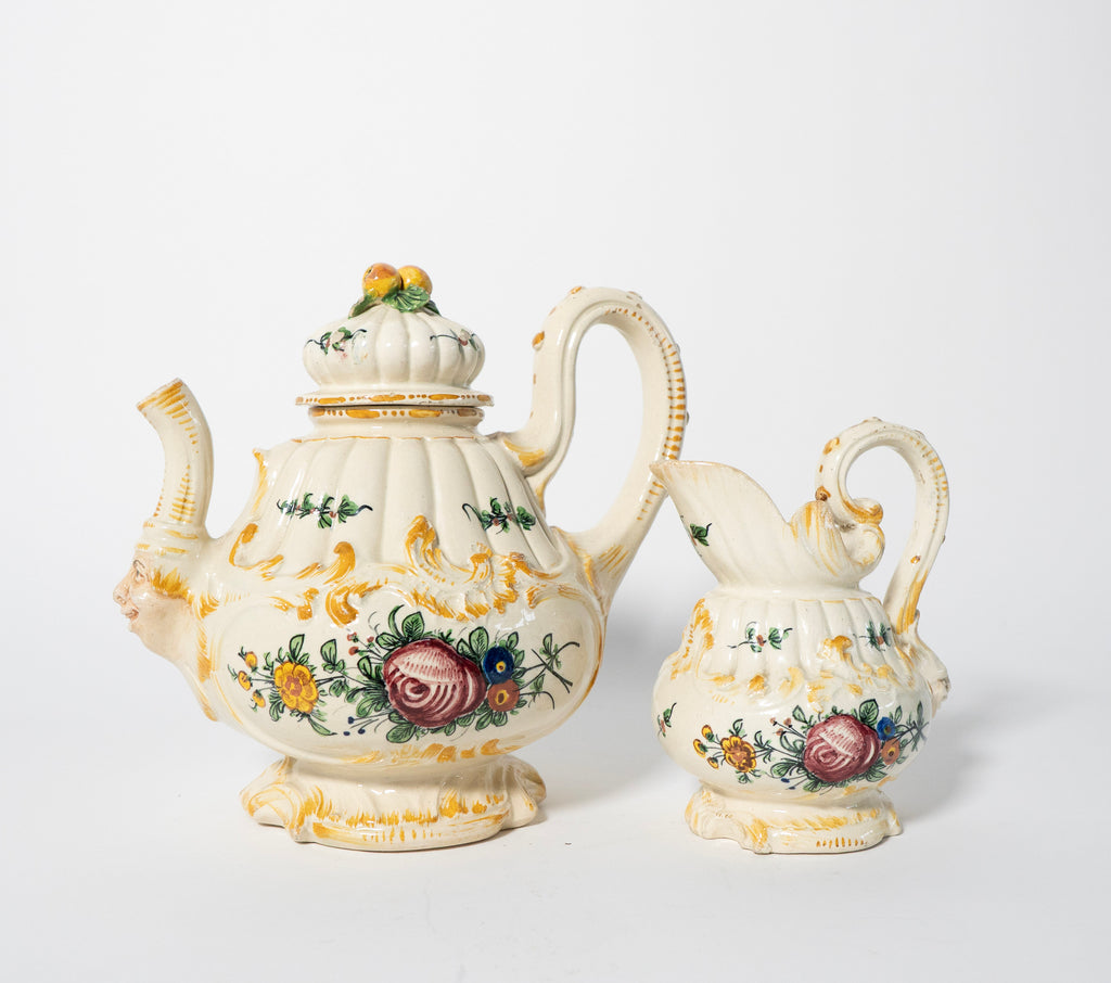 Decorative ceramic teapot and matching creamer with floral patterns on a white background