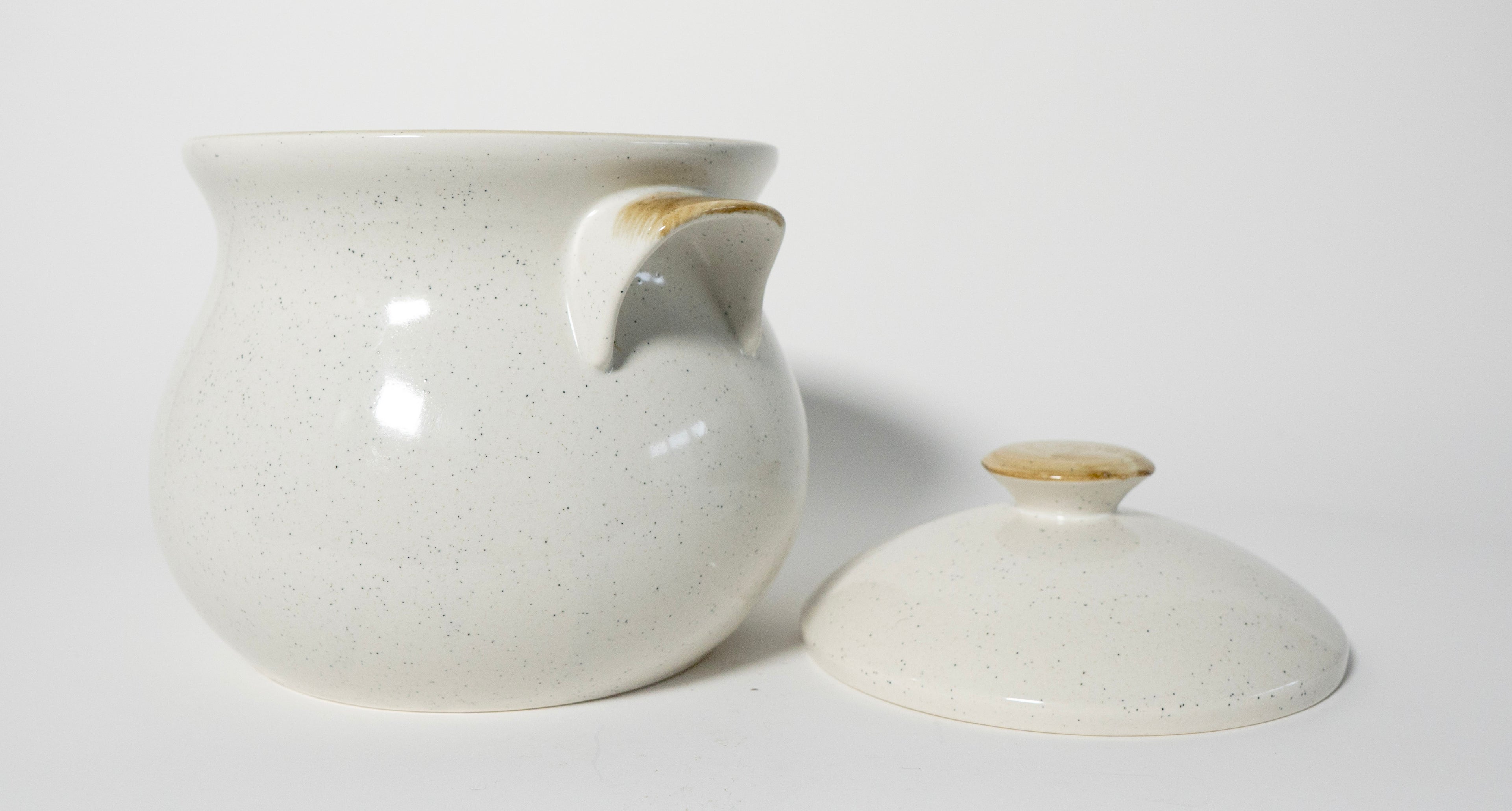 White ceramic pot with a lid on a white background