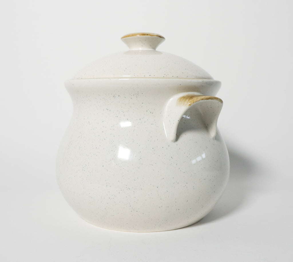 White ceramic pot with gold accents on a light gray background
