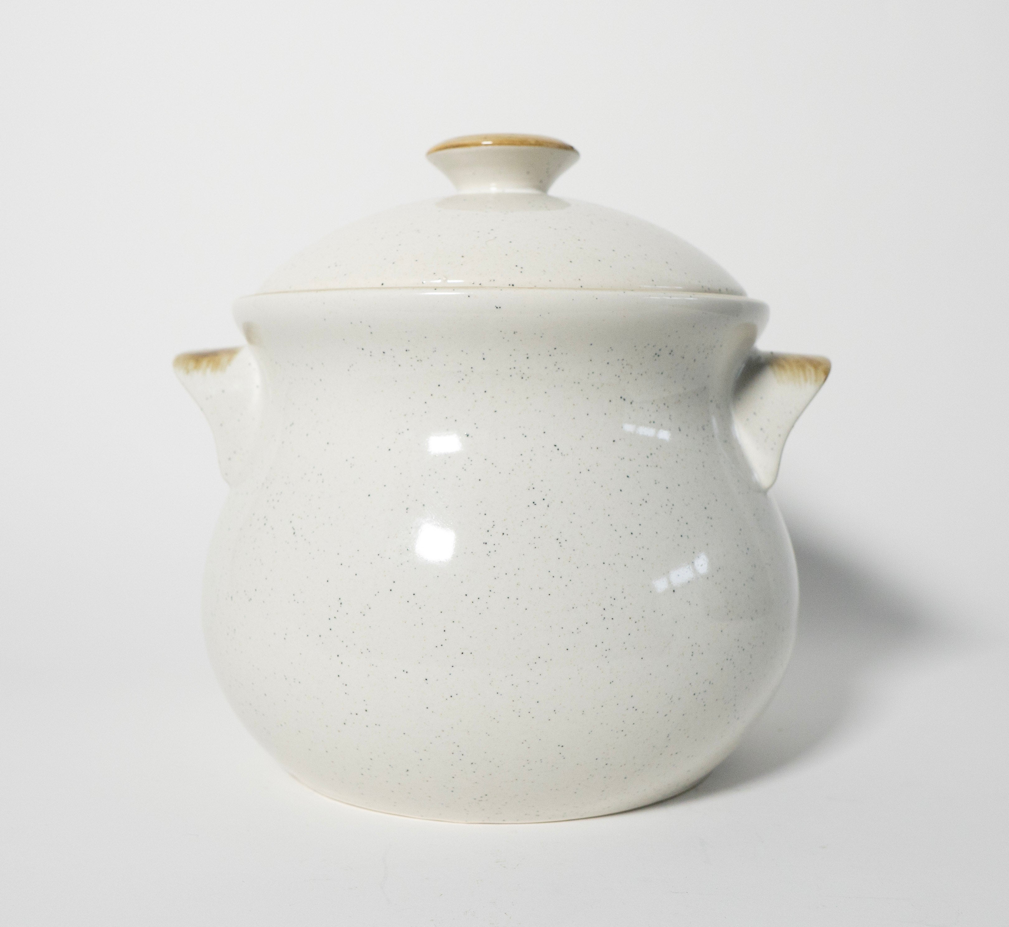 White ceramic pot with lid on a light gray background