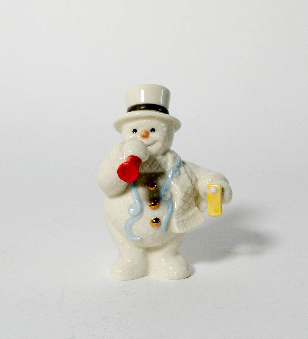 Small ceramic snowman figurine with a top hat, red carrot nose, and gold pocket watch on a white background.
