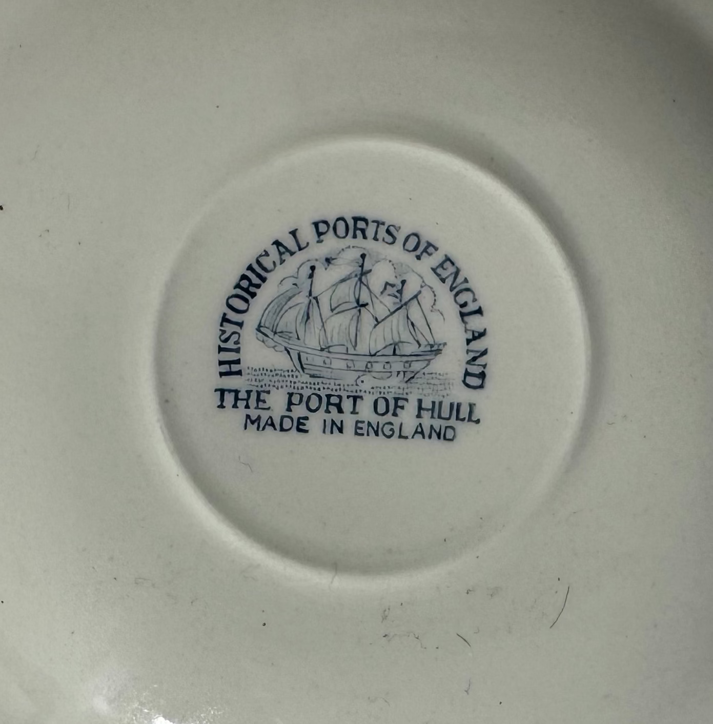 White ceramic plate with blue text and logo on a white background