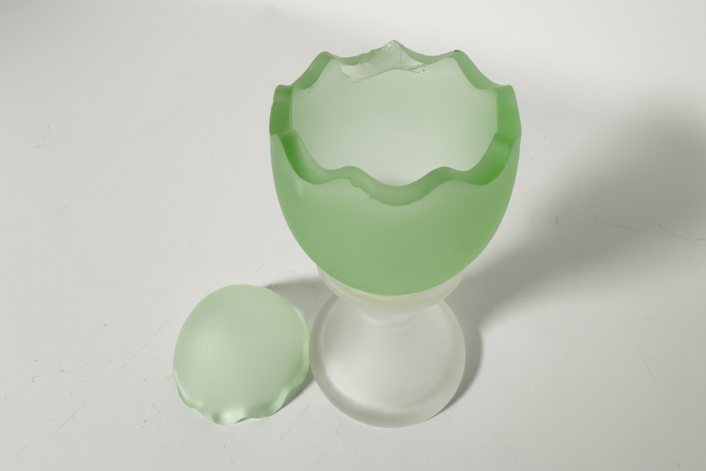 Green glass egg-shaped container with a matching lid on a white background